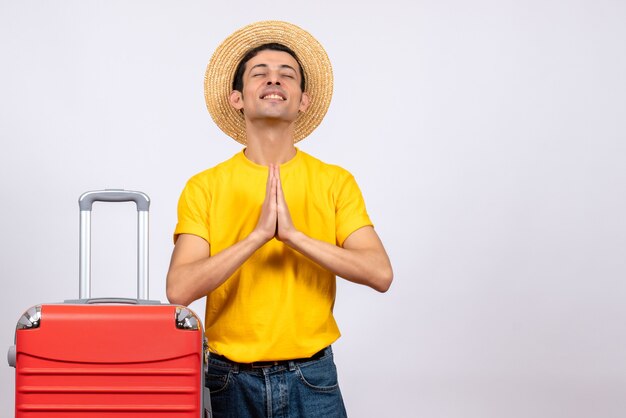 Вид спереди счастливый молодой человек с желтой футболкой и чемоданом, взявшись за руки вместе