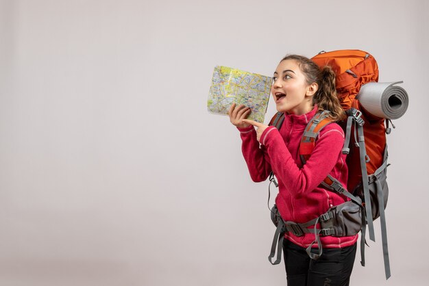 Вид спереди счастливого молодого путешественника с большим рюкзаком, держащего карту