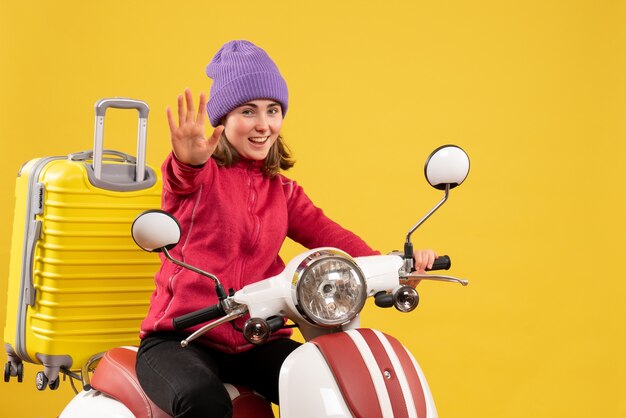 Front view happy young woman on moped making stop sign