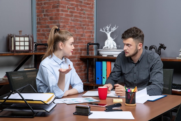 Front view of hardworking and confident professional team discussing one issue in the documents in the office