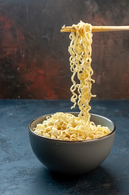 Front view hashi chopsticks ramen noodles in bowl on dark background