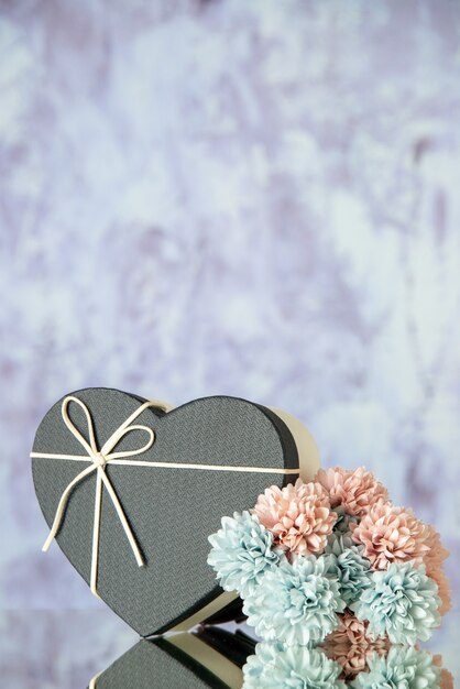 Front view of heart box colored flowers on grey abstract background with free space