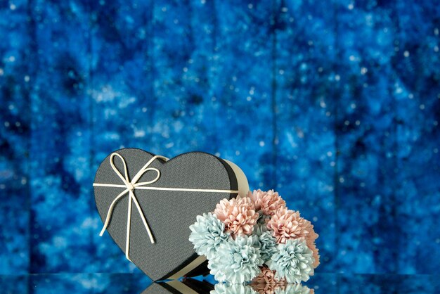 青いぼやけた背景に黒いカバー色の花と正面のハートギフトボックス