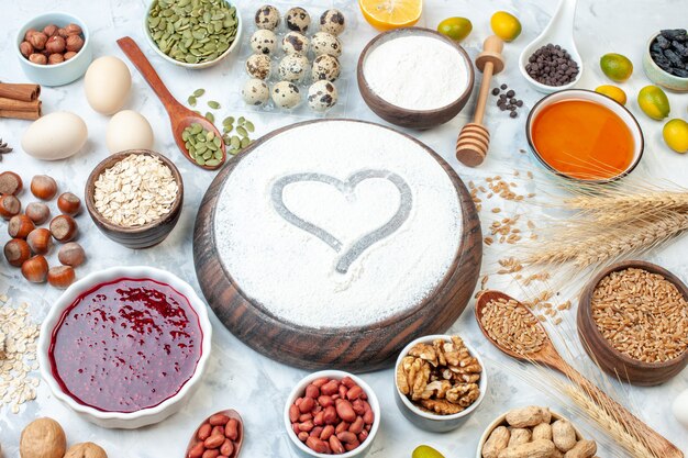 Front view heart shaped flour with jelly eggs different nuts and seeds on white background dough sugar cake photo nut sweet color biscuit