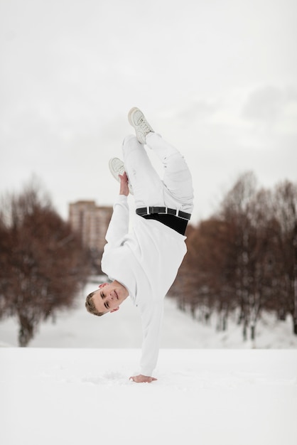 Front view of hip hop performer posing on one hand outside