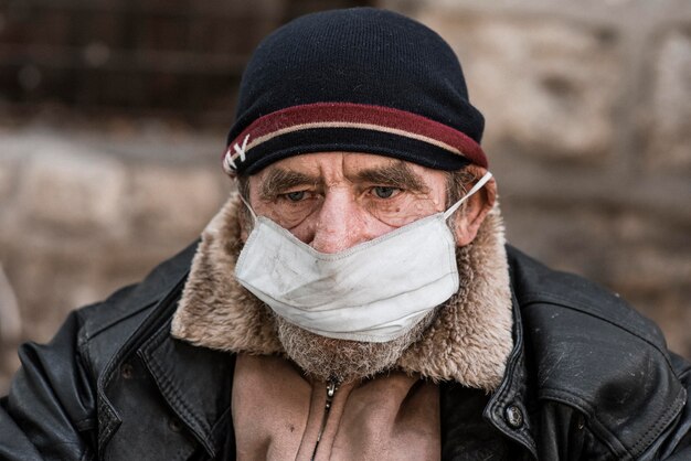 Front view of homeless man outdoors with medical mask