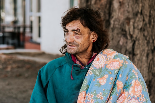 Vista frontale di un senzatetto con coperta sulla spalla