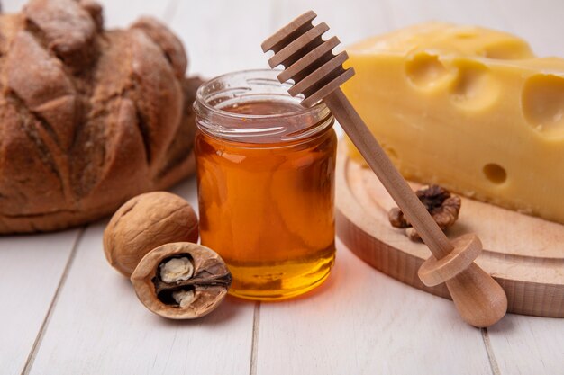 Front view honey in a jar with cheese  walnuts and black bread on a white background