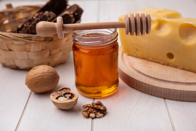 Front view honey in a jar with cheese  walnuts and black bread on a white background