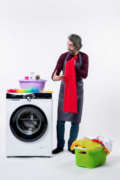 Front view housekeeper man holding red towel standing near washing machine on white background