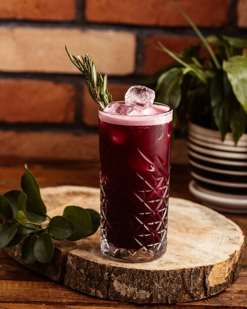 A front view iced cherry cocktail with ice-cubes on the brown wooden desk drink juice cocktail