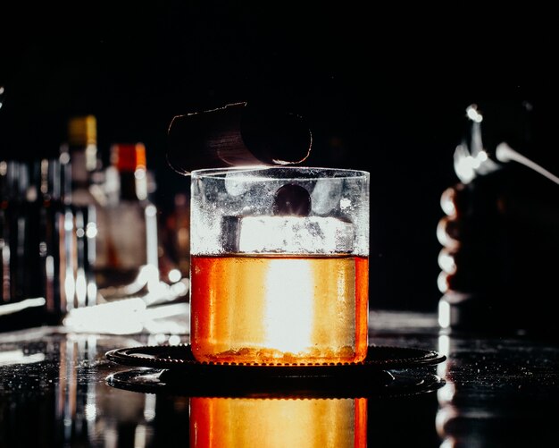 暗いバーの机の上の小さなガラスの中の正面図アイスドリンクドリンクジュースアルコールウォーターバー