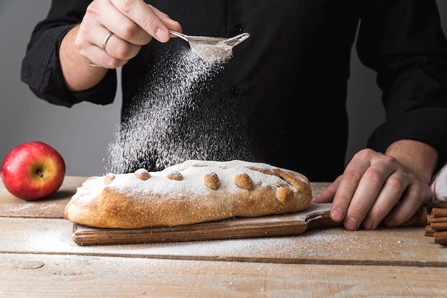 Front view individual pouring sugar on pastry