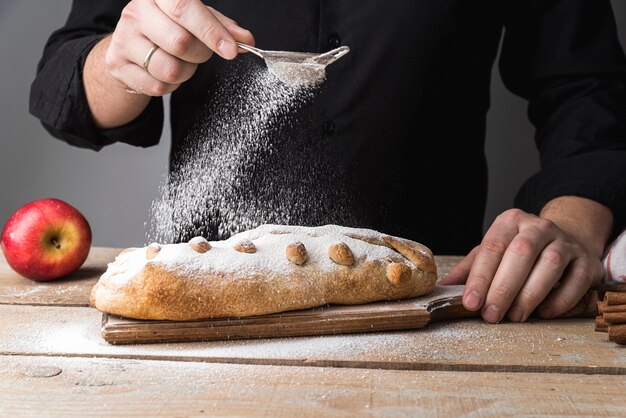 Front view individual pouring sugar on pastry