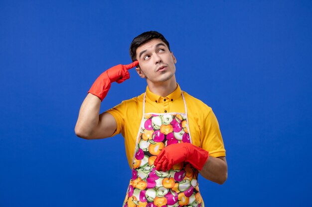 Front view interested male housekeeper in apron putting finger to his temple 