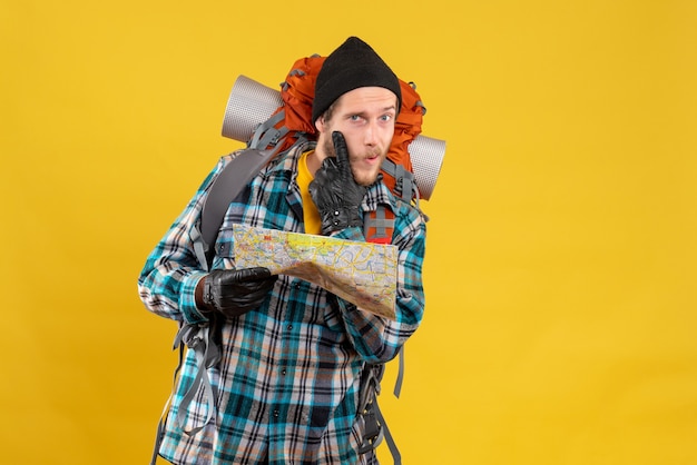 Front view of interested young backpacker with leather gloves holding map