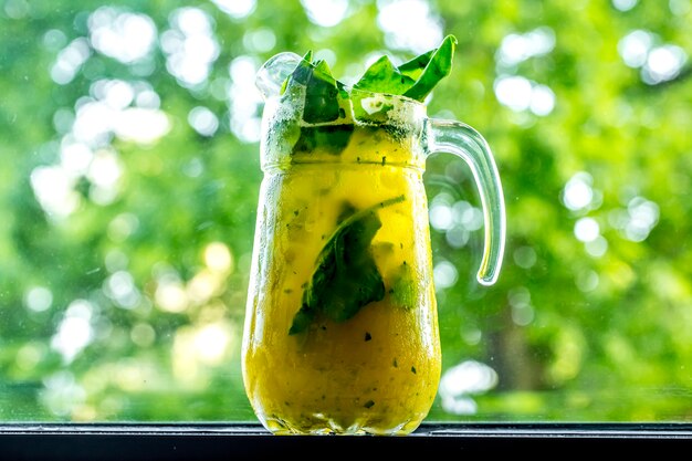 Front view invigorating lemonade in decanter with lemon lime and spinach