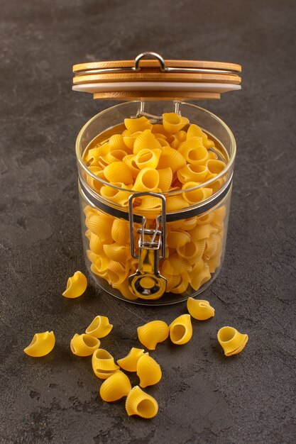 Вид спереди итальянская сухая паста желтого сырья внутри чаши, изолированных на темном