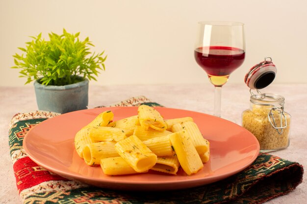 カラフルなカーペットとピンクの生パスタとワインのグラスと一緒にピンクプレート内の正面イタリアパスタおいしい食事