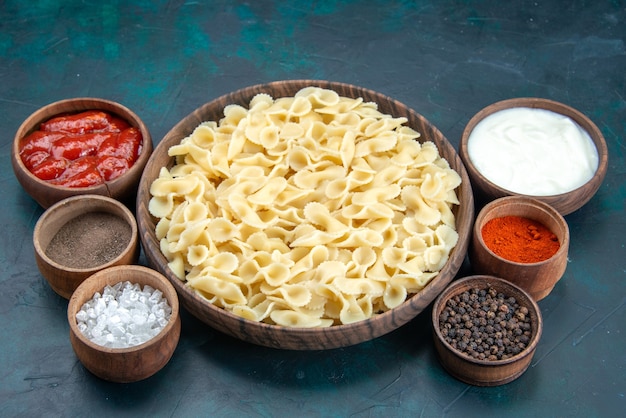 Pasta italiana vista frontale con diversi condimenti sul blu