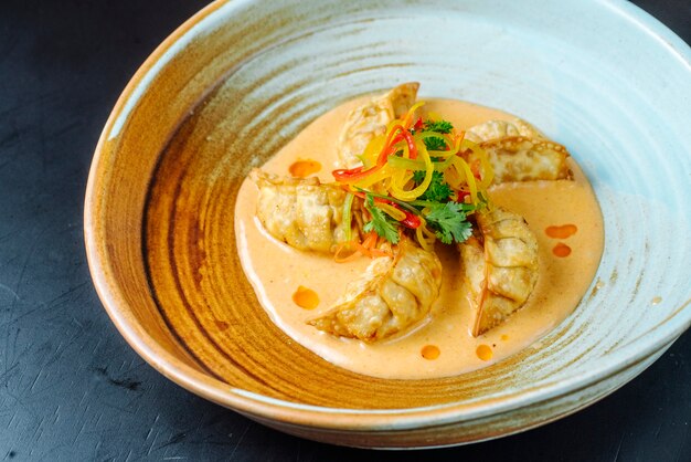 Front view japanese fried gedza dumplings in sauce with greens in a plate