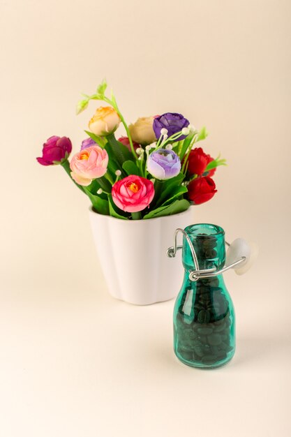 A front view jar with coffee and flowers on the pink table coffee color flower seed