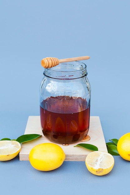 Free photo front view jar with honey surrounded by lemon