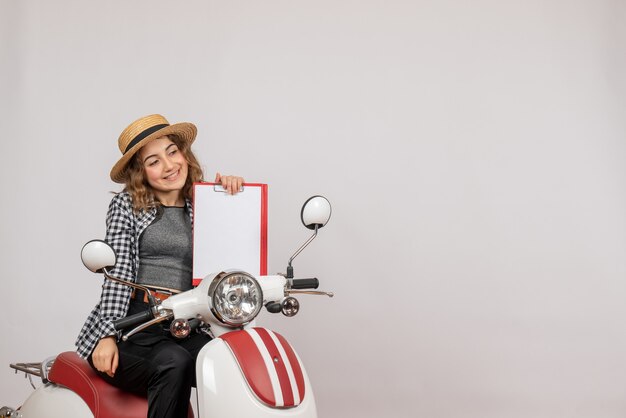 빨간 클립 보드를 들고 오토바이에 즐거운 여행자 소녀의 전면보기