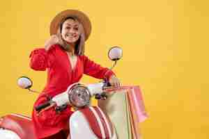 Foto gratuita vista frontale della donna allegra in vestito rosso sui sacchetti della spesa della holding del ciclomotore