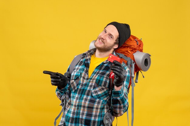 Front view of joyful young man with backpacker holding discount card