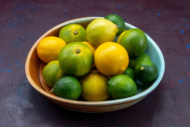 正面図ジューシーな新鮮な柑橘類レモンとみかんの暗い机の柑橘類の熱帯のエキゾチックなオレンジ色の果実