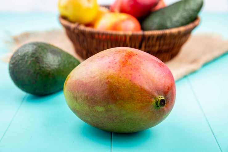 Free Photo front view of juicy mango with a bucket of fresh fruits on sack cloth on blue surface