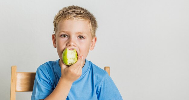 Front view kid bitting a green apple