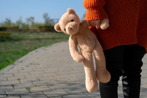 Free photo front view kid holding teddy bear outdoors