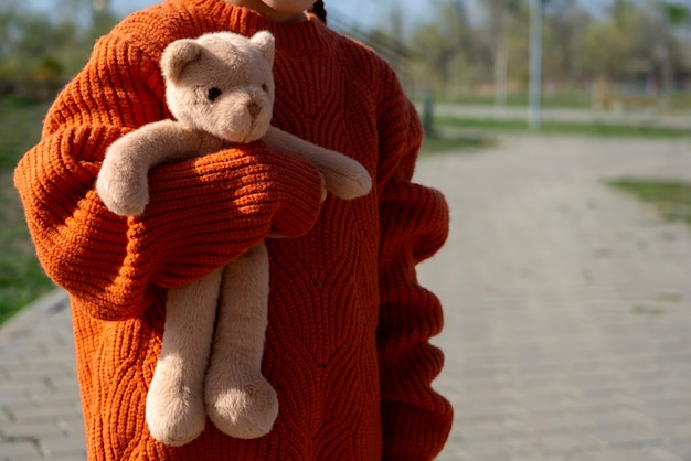 Front view kid holding teddy bear outdoors