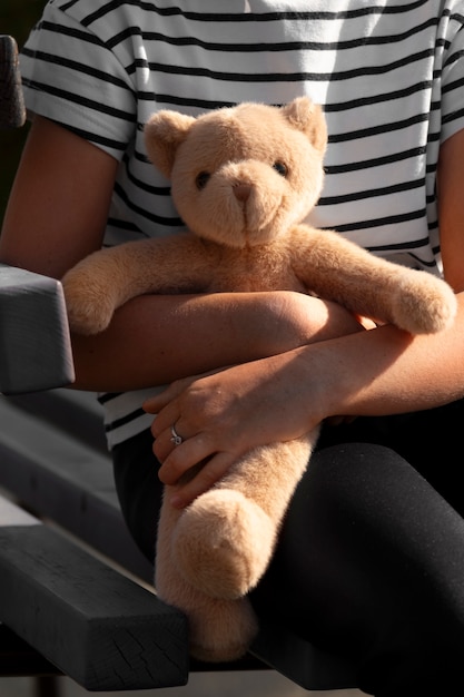 Free photo front view kid holding teddy bear outdoors
