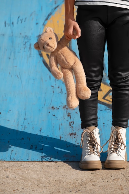 Free photo front view kid holding teddy bear outdoors