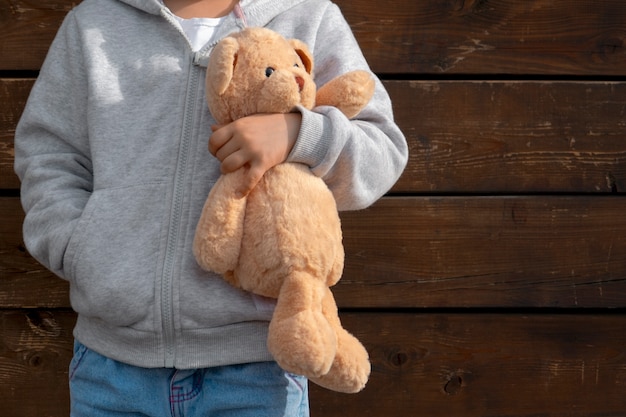 Front view kid holding teddy bear outdoors