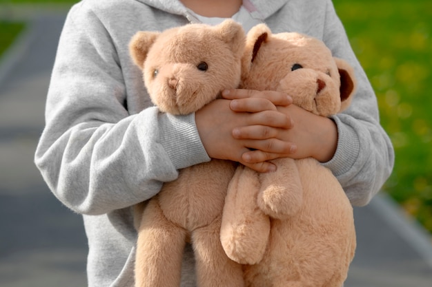 Передний вид ребенка с плюшевым медведем на открытом воздухе