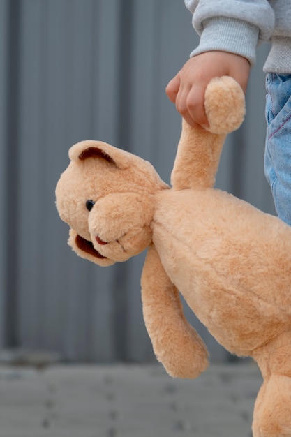 Front view kid holding teddy bear outdoors