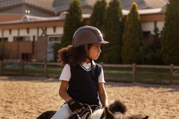 Free photo front view kid learning to ride horse