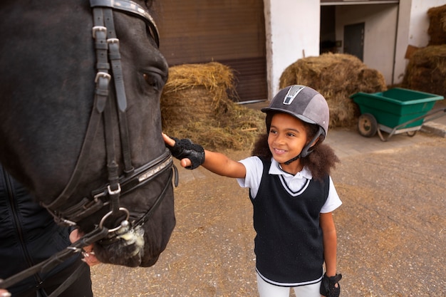 Бесплатное фото Ребенок, вид спереди, учится кататься на лошади