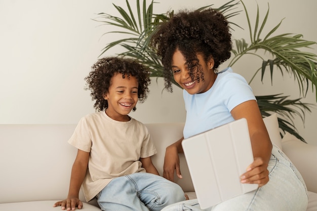 Front view kid and mother with tablet