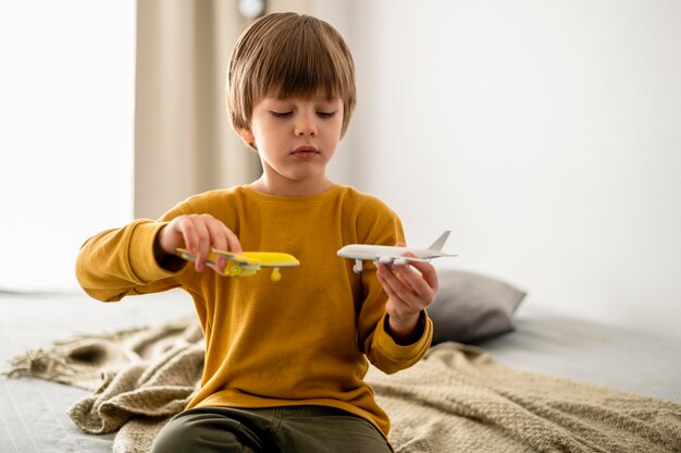 Front view of kid playing with airplane figurines