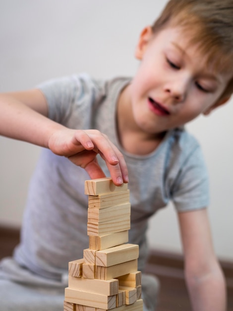 Front view kid playing with wooden tower game