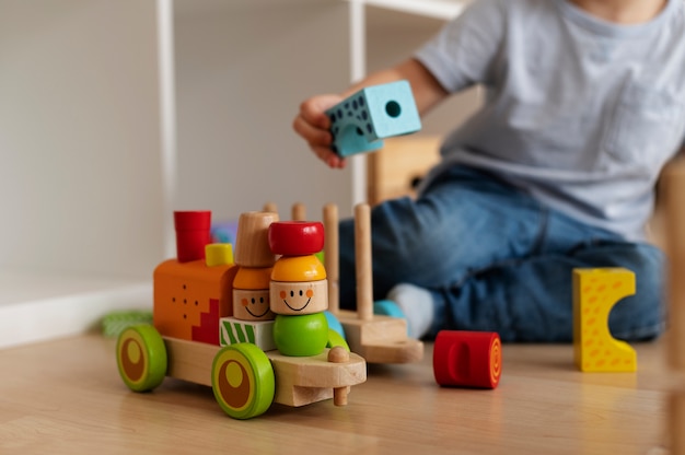 Бесплатное фото Ребенок, вид спереди, играет с деревянными игрушками