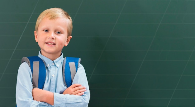 Free photo front view kid standing next to a blackboard