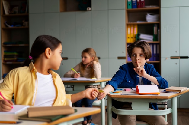 Vista frontale dei bambini che tradiscono a scuola