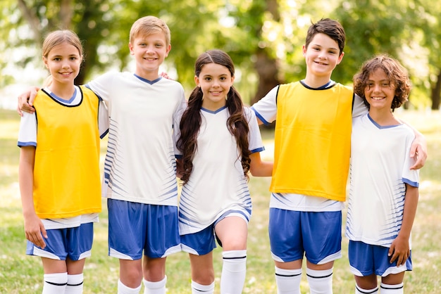 Front view kids in football sportswear holding each other