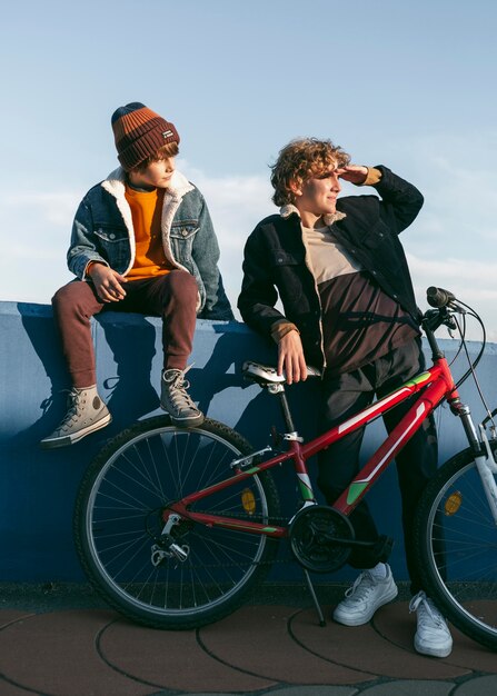 Front view of kids with bike outdoors
